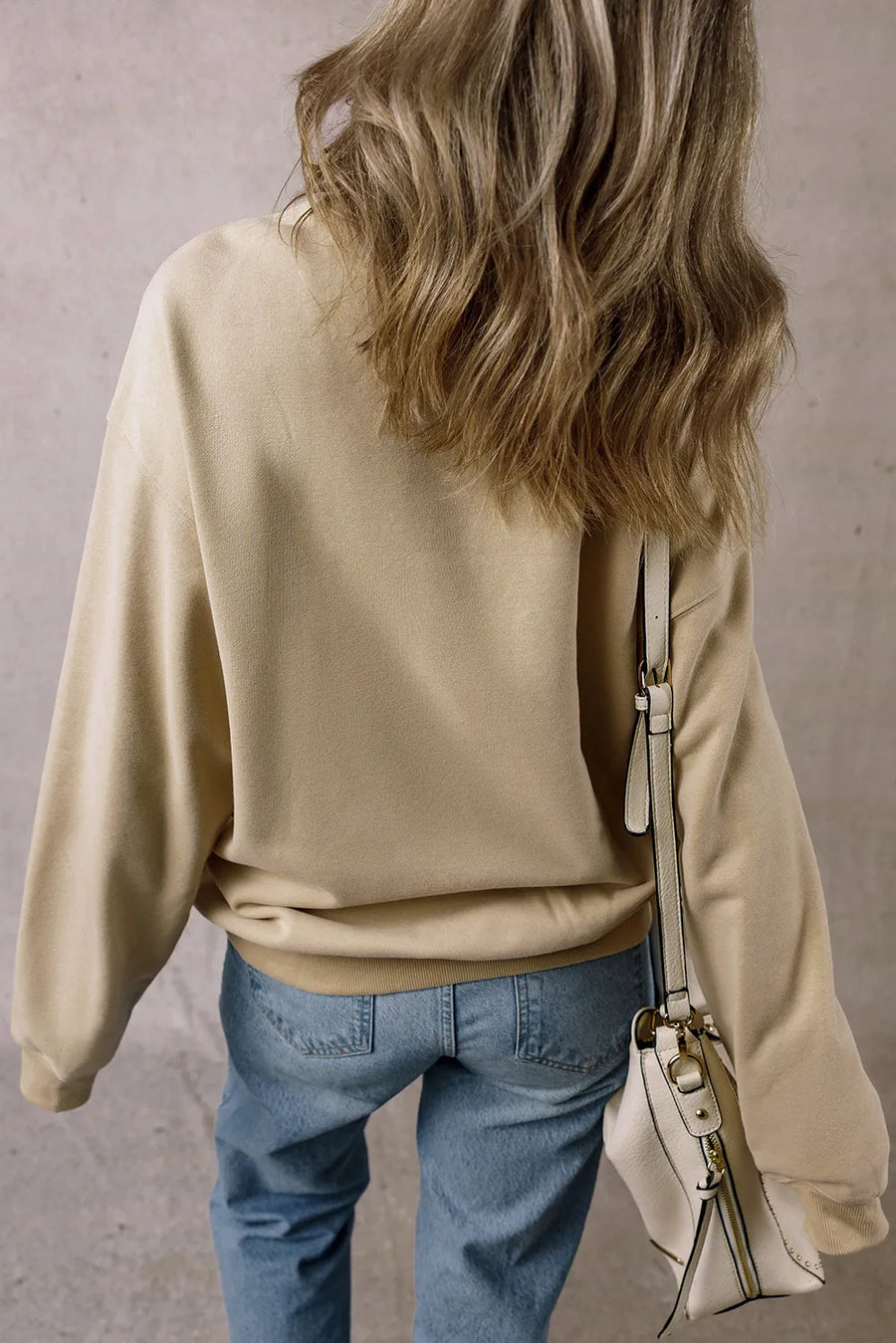 Khaki graphic bow sweatshirt with crew neck and long sleeves, styled with jeans.