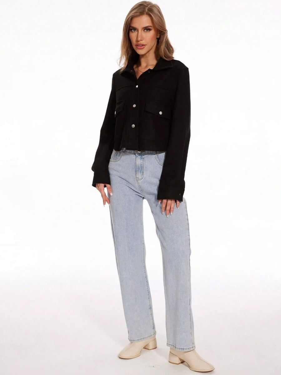Black trucker jacket with snap buttons and chest pockets, long sleeves, cropped length.