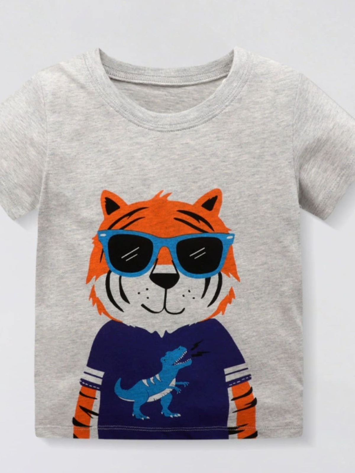 Toddler grey cotton crew neck t-shirt with a tiger wearing sunglasses and a blue dinosaur graphic shirt.