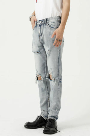 Light wash denim jeans with ripped knees and a slim fit, styled casually.