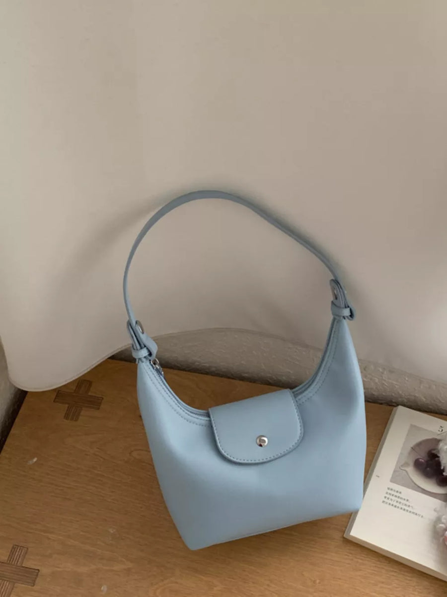 Elegant mini crescent hobo bag in blue with a flap closure and silver buckle.