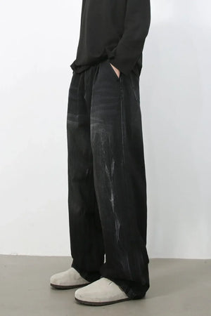 Dark wash pleated wide-leg denim trousers with distressed details