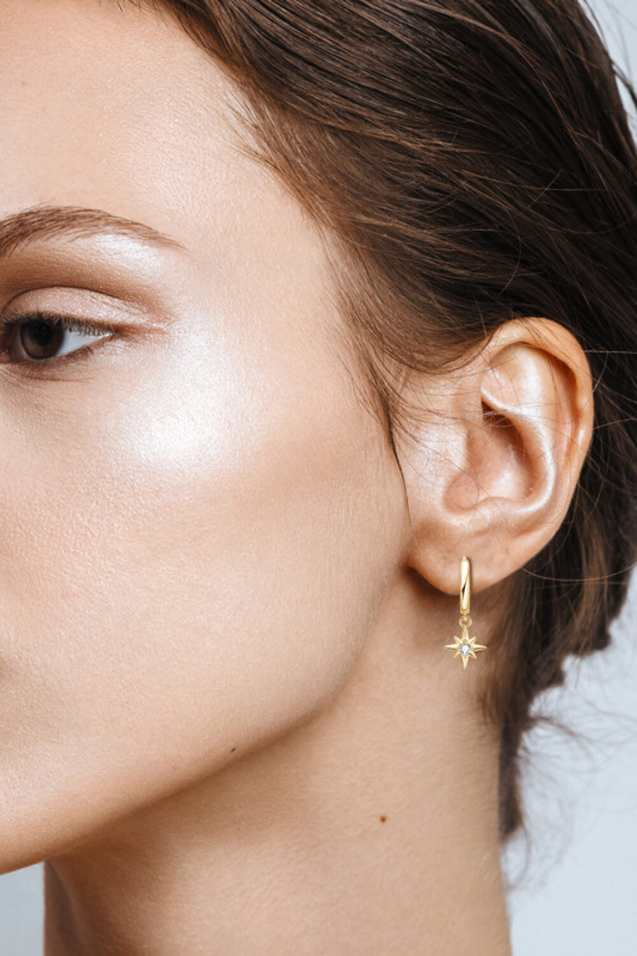 Gold hoop earrings with a starburst charm and a crystal accent.