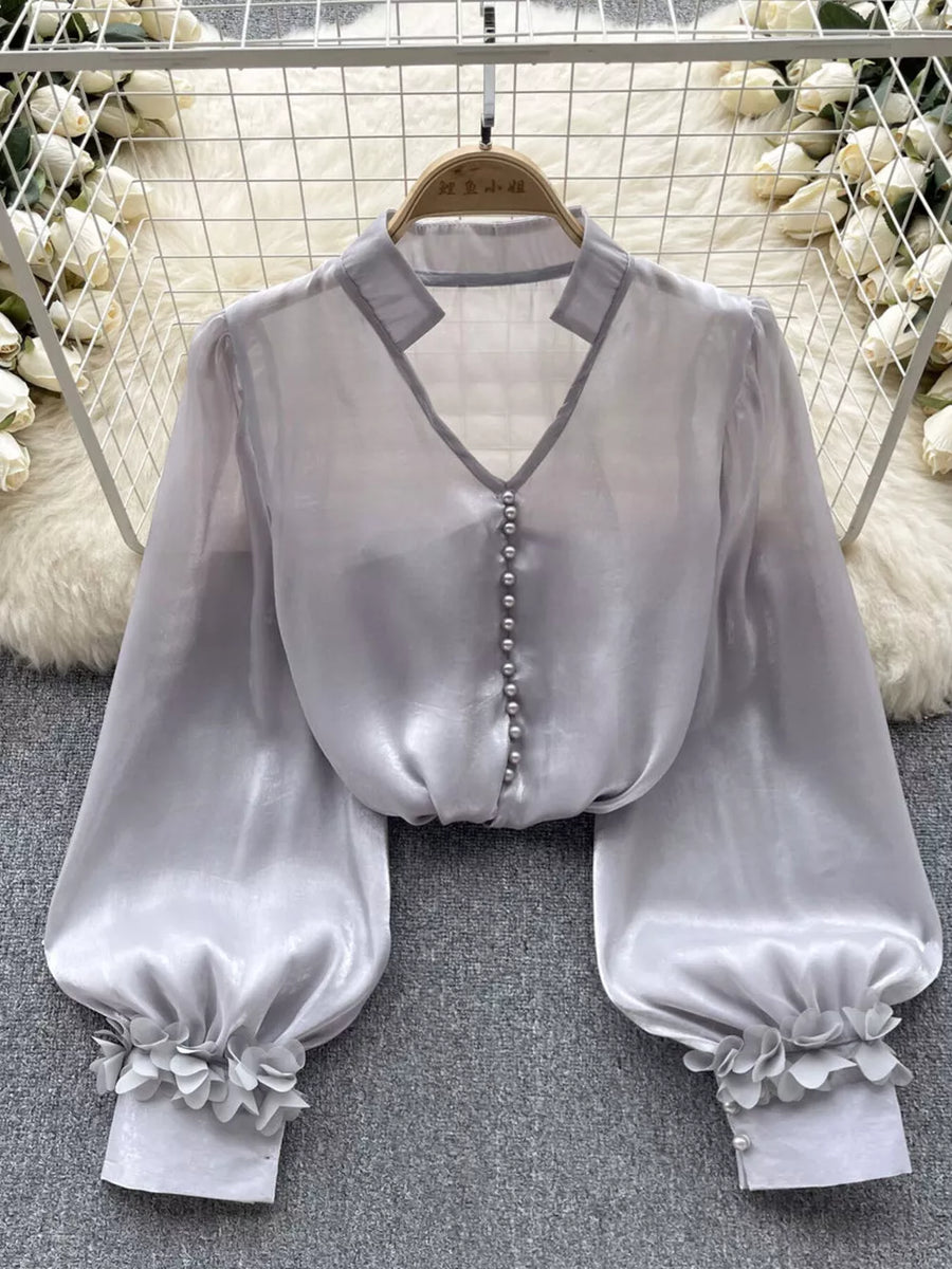 Gray sheer button-down shirt with pearl buttons and floral appliqué cuffs.