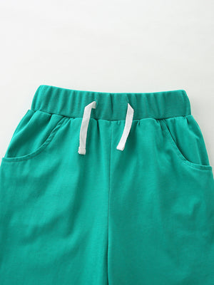 Green cotton toddler shorts with elastic waistband and white drawstring.
