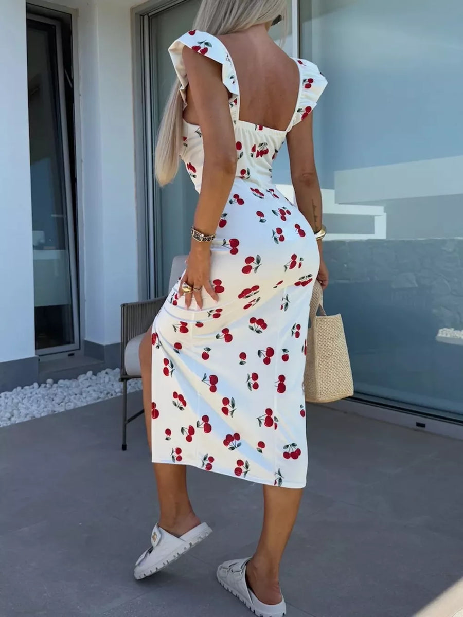 White midi dress with cherry print, sweetheart neckline, ruffled cap sleeves, and thigh slit.
