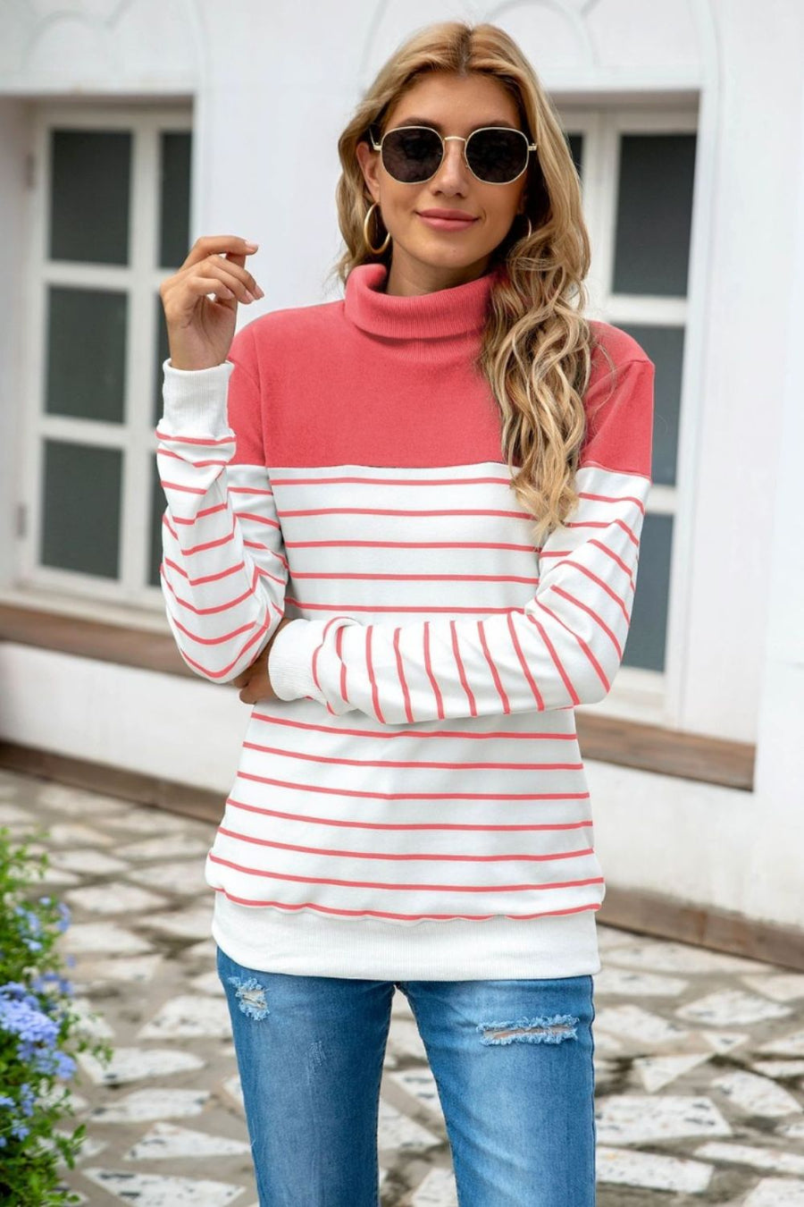 Colorblock stripe turtleneck knit sweater with coral and white horizontal stripes.