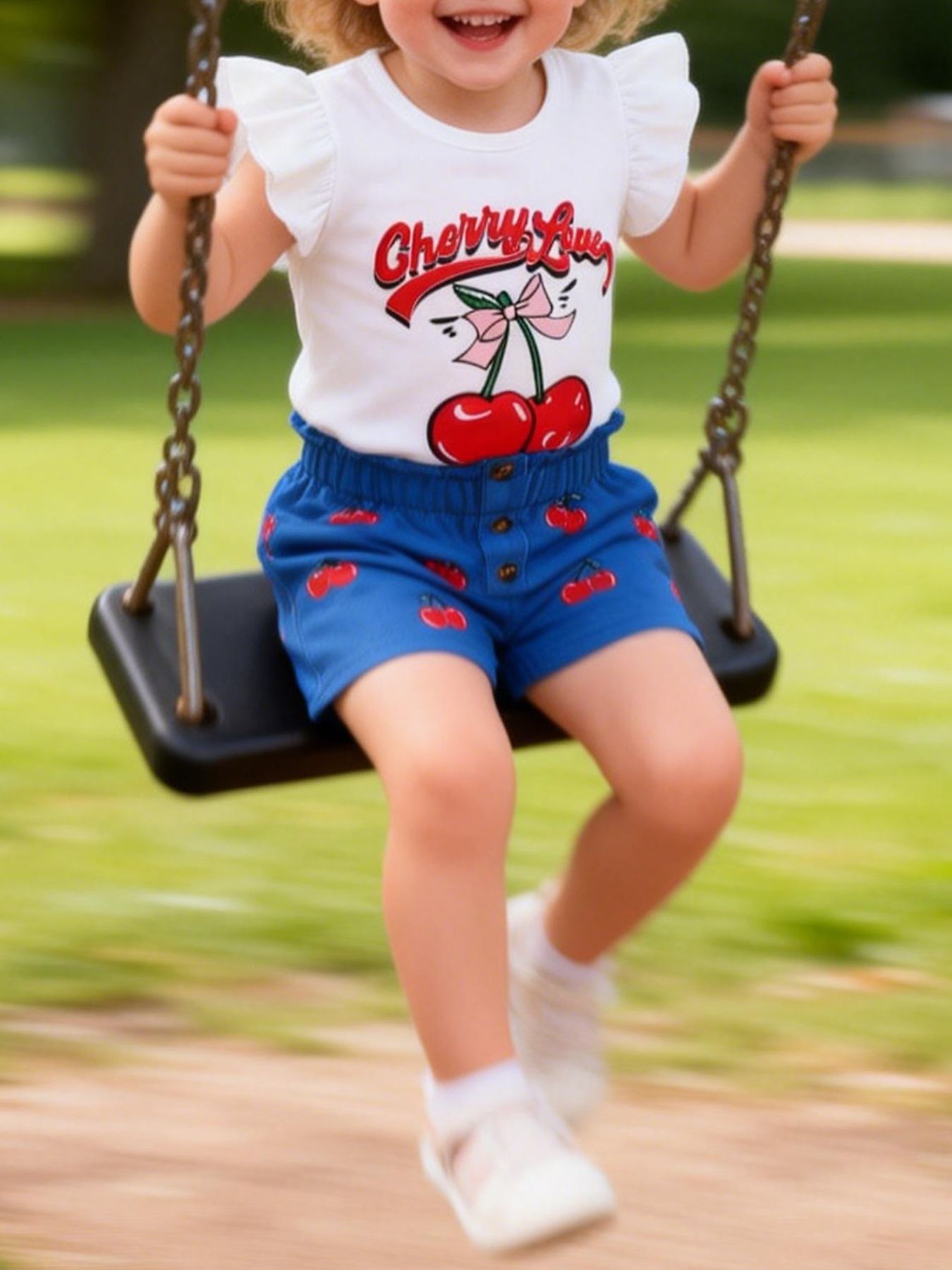Girls' white cherry graphic tee with ruffled sleeves and royal blue cherry print shorts.