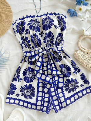 Blue floral tie-waist strapless romper with a ruffled hem and tie detail.