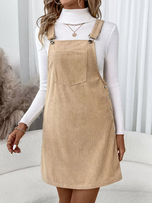 Tan corduroy overall dress with a front pocket and button side details.