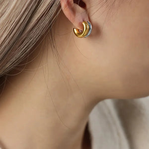Dual-tone sculptural C-hoop earrings in gold and silver, a modern statement accessory.