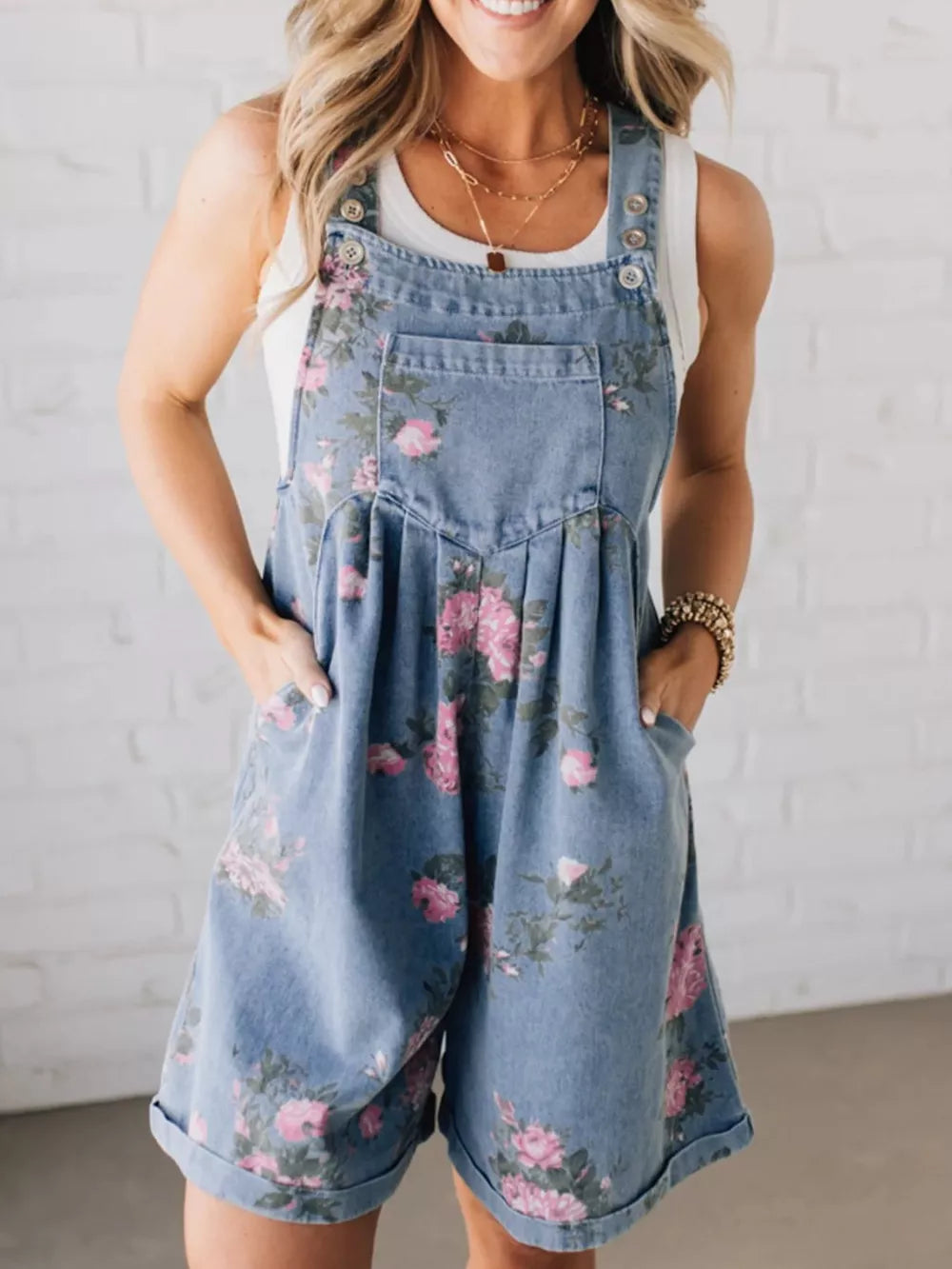 Denim overalls shorts with pink floral print, button straps, and cuffed hems.