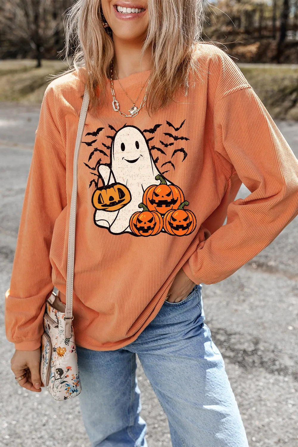 Corduroy crewneck sweatshirt in sherbet with ghost and pumpkin graphic.