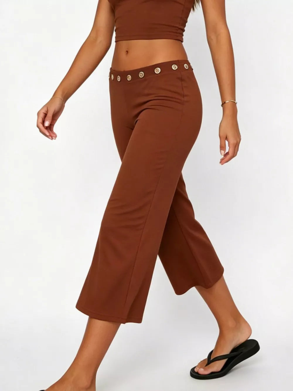 Dark brown flared hem capri pants with button detail at the waist.