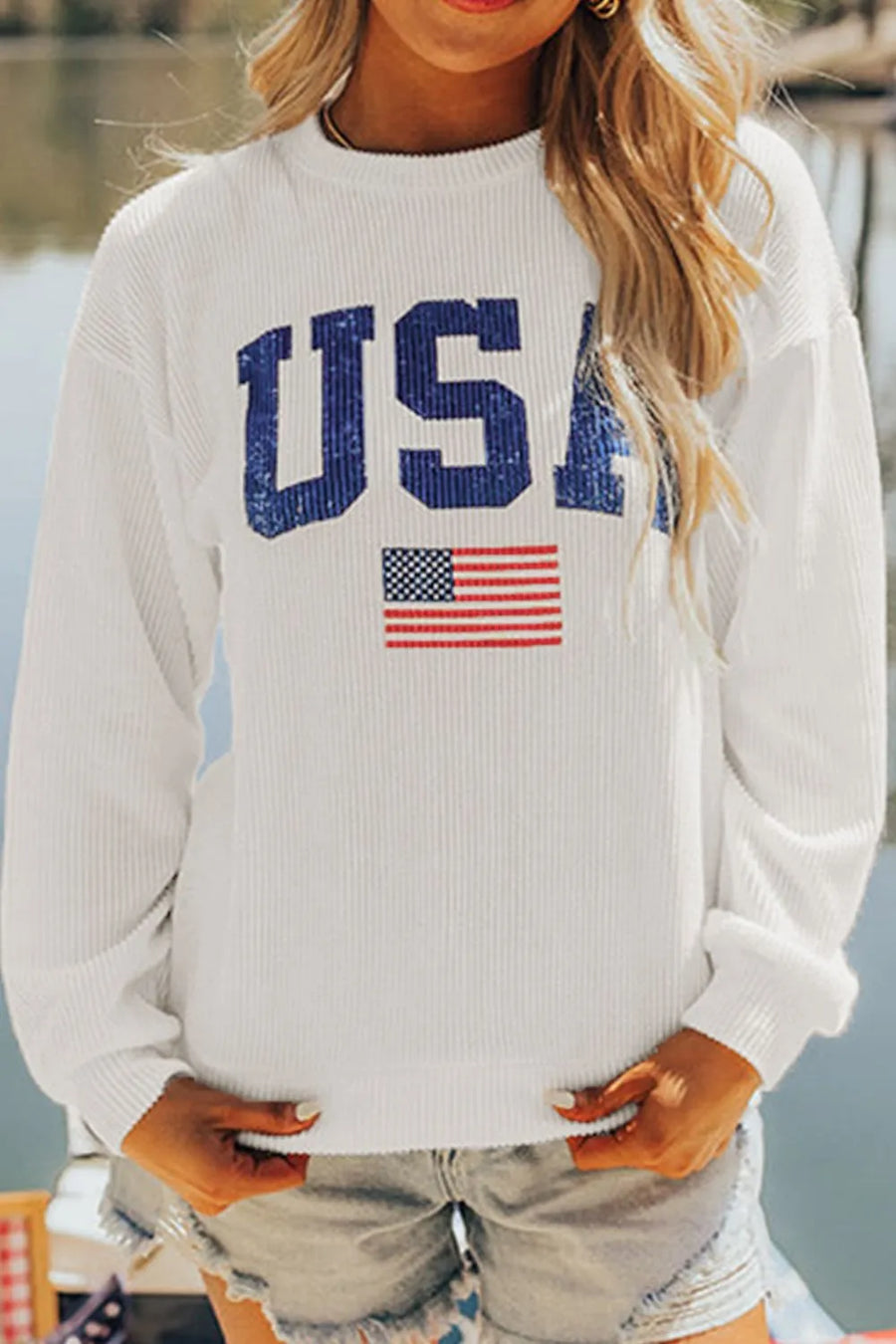 White ribbed knit sweatshirt with distressed USA graphic and American flag detail.