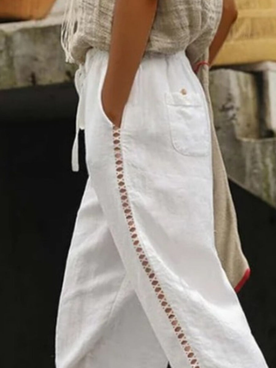 White relaxed cropped pants with hollow out trim detail and drawstring waist.