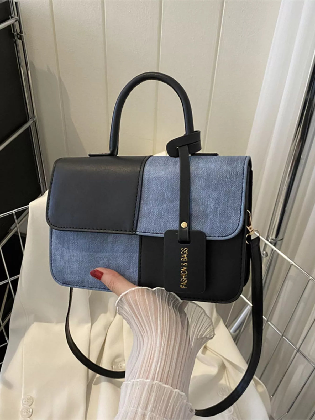 Chic two-tone black and blue PU leather crossbody handbag with top handle and tag.