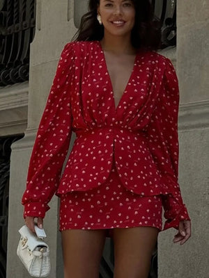 Red printed mini dress with plunging neckline, long sleeves, and cinched waist.