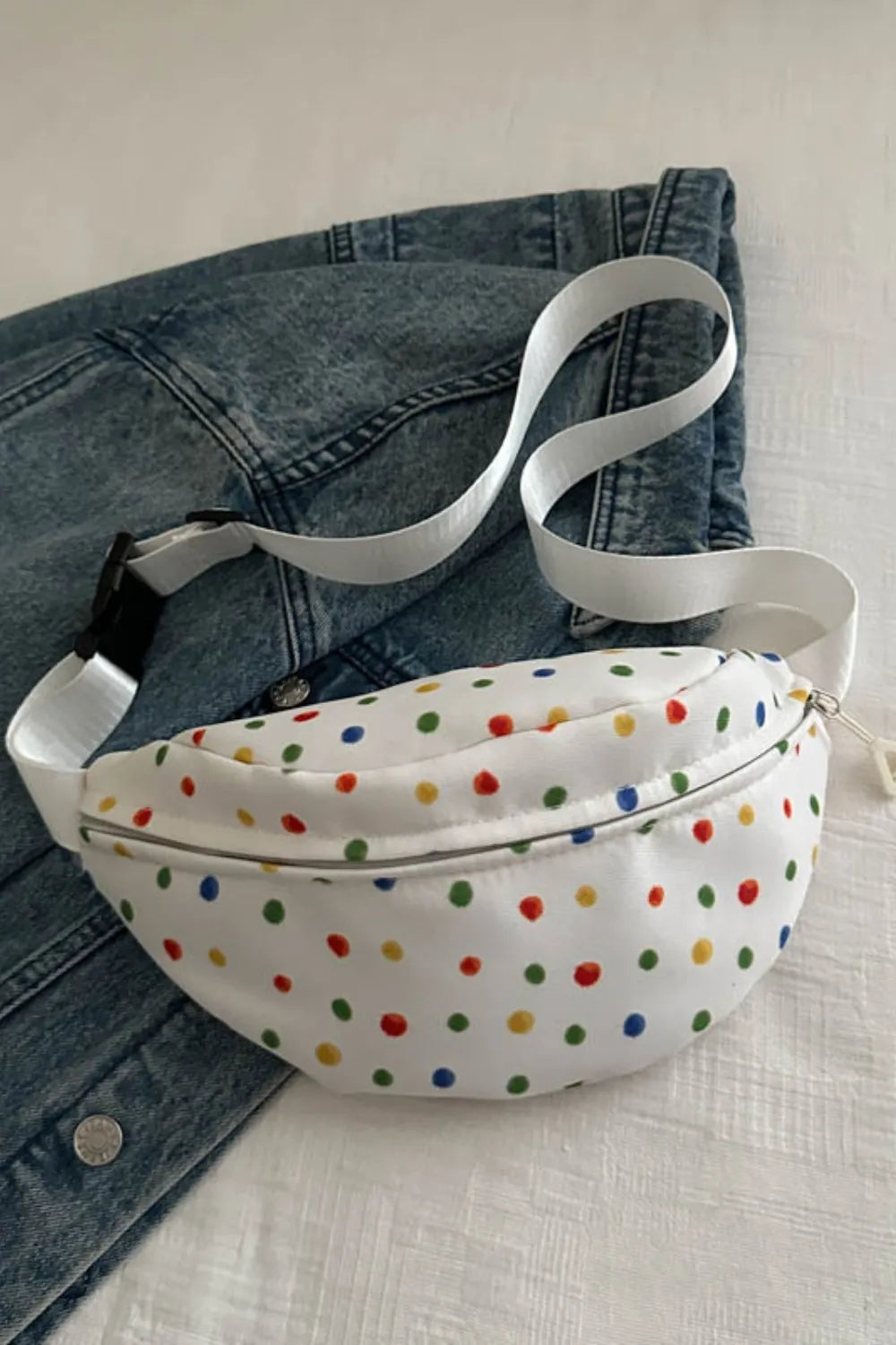 White belt bag with colorful polka dots and a white strap.