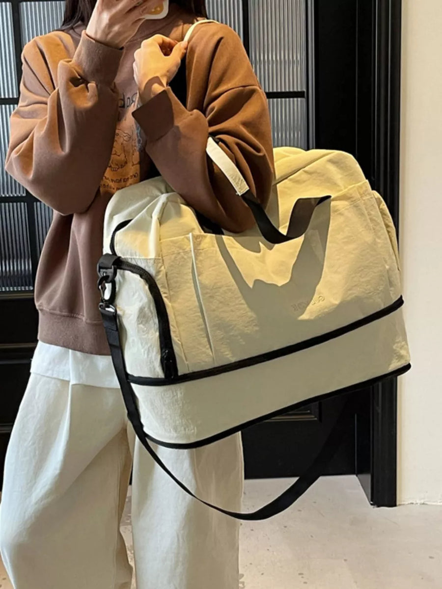 Off-white Oxford cloth travel tote bag with black trim and shoulder strap.