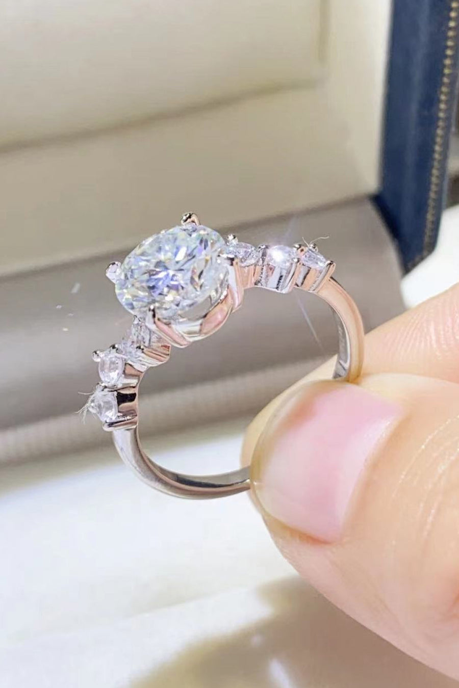 Silver moissanite halo ring with a large center stone and smaller accent stones.