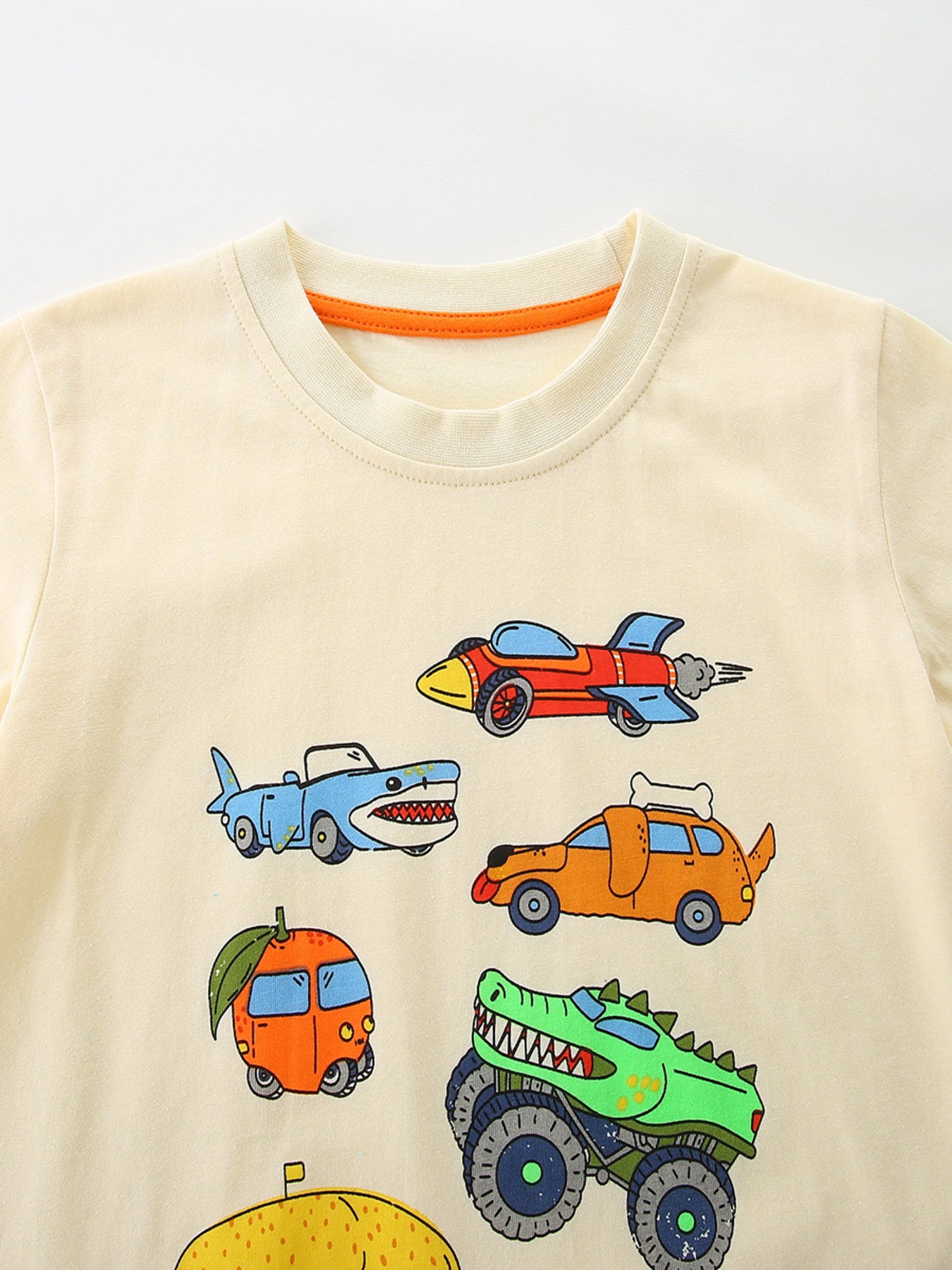 Cream cotton toddler t-shirt with cartoon vehicles including a shark car, rocket car, dog car, and monster truck.