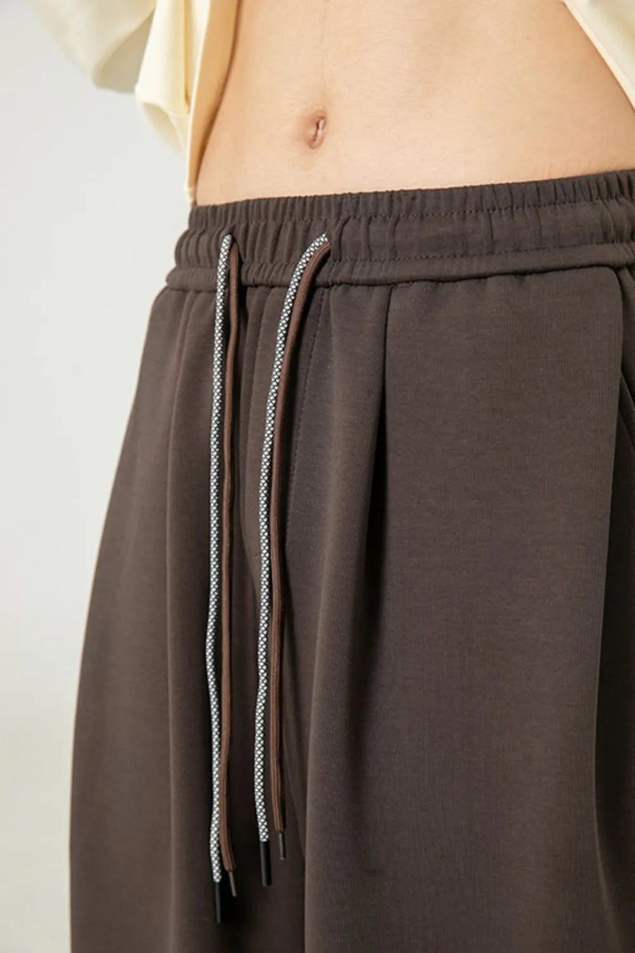 Oversized lounge trousers in coffee brown with drawstring and drape-front detail.