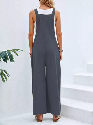 Dark gray wide-leg romper with pockets, square neckline, adjustable straps, buttoned sides, and wide legs.