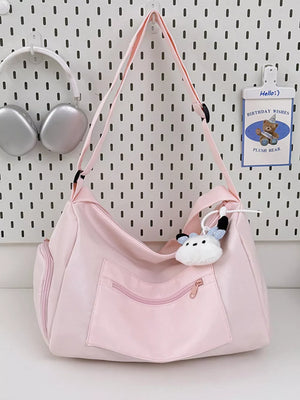 Blush pink travel pouch with adjustable strap and multiple zippered pockets, featuring a cute plush charm.