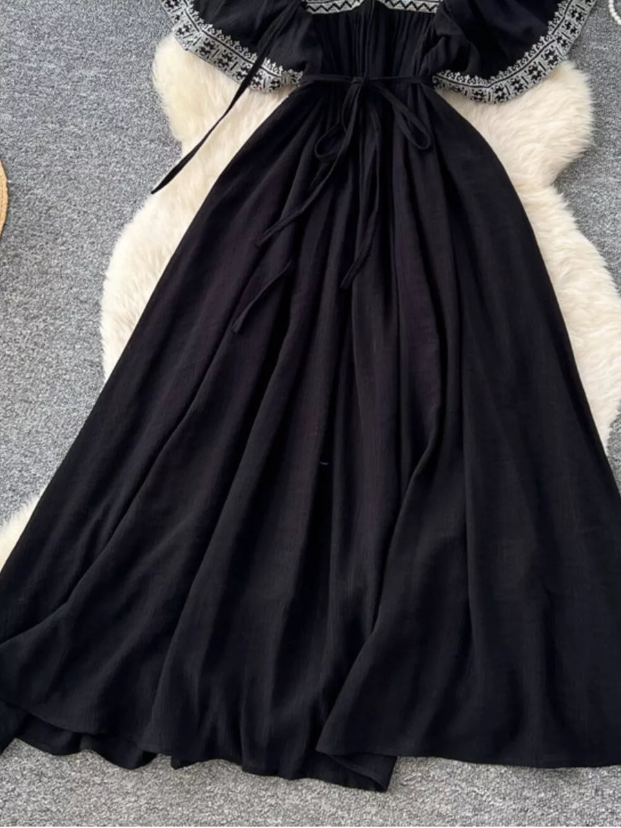 Black embroidered V-neck maxi dress with a tie waist and flowing skirt.