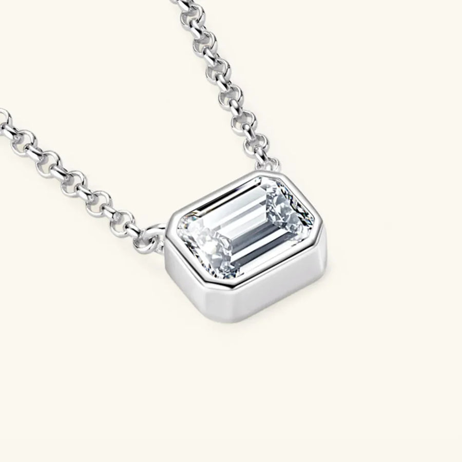 Silver necklace with emerald cut moissanite in a bezel setting.
