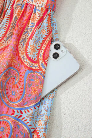 Paisley print boho dress with a phone in the pocket, featuring coral and blue floral patterns.