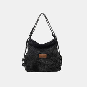 Black denim hobo bag with leatherette patch and adjustable straps.