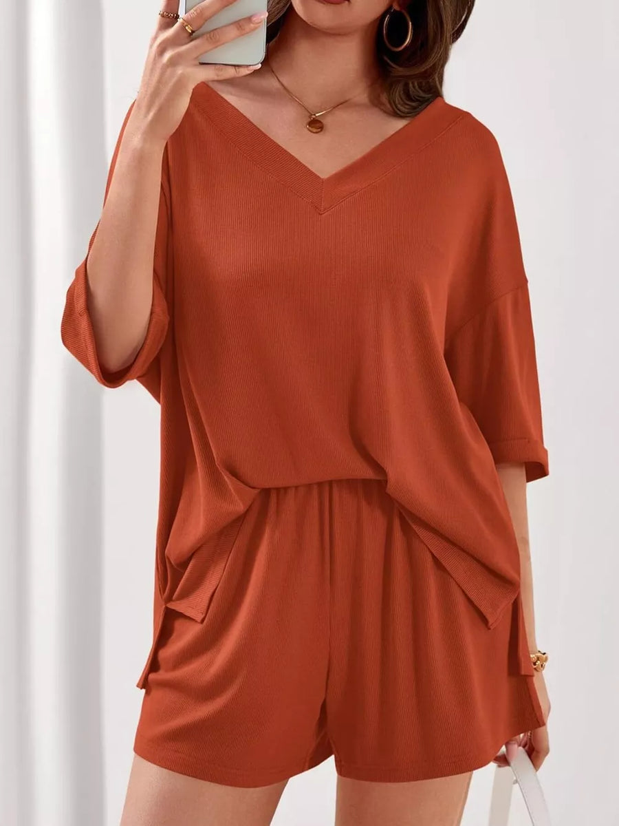 Orange-red V-neck two-piece lounge set with cuffed sleeves and drawstring shorts.