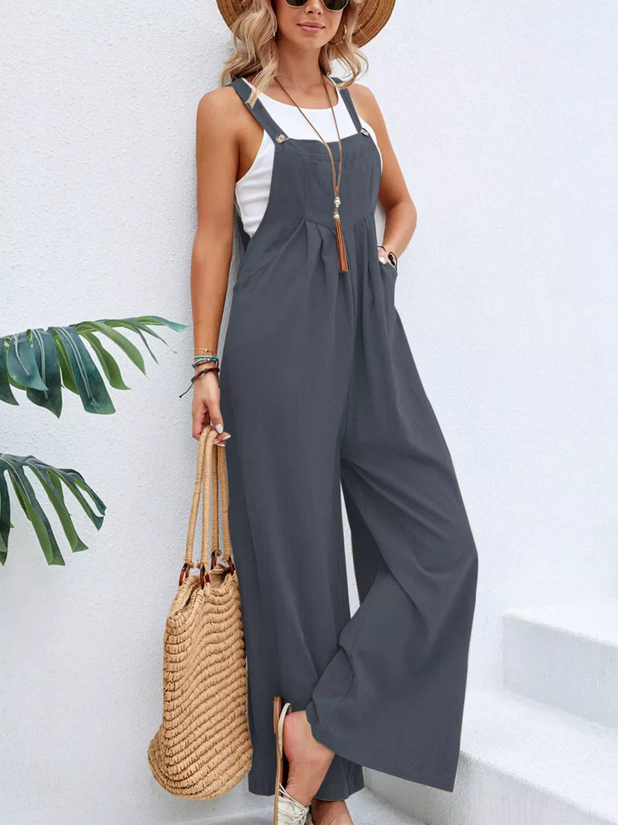 Dark gray wide-leg romper with pockets and adjustable straps, worn with a white tank top.