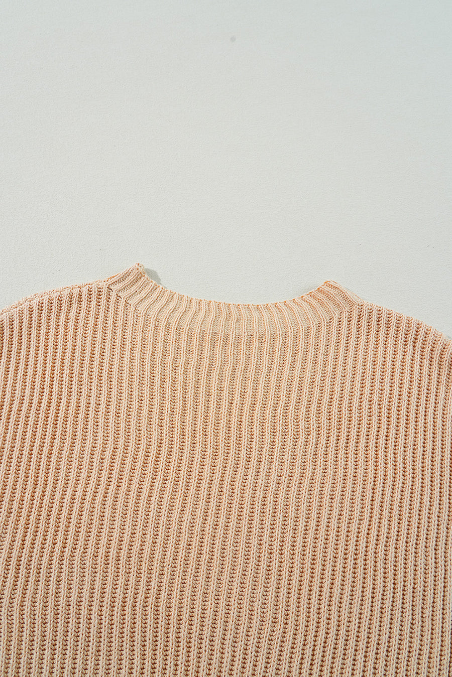 Tan ribbed knit pullover sweater with asymmetric hem detail.
