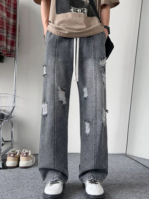 Oversized distressed wide-leg jeans in dark gray denim with a drawstring waist.