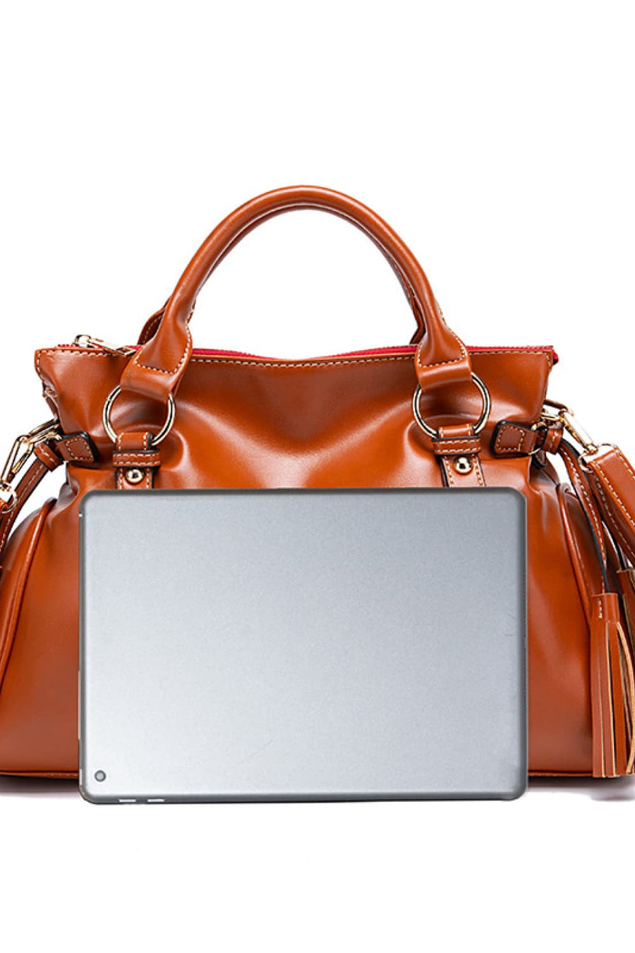 Caramel structured satchel bag with tassel detail and silver tablet for size reference