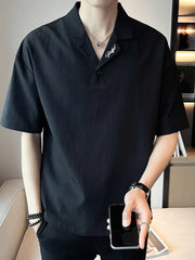 Black cotton polo with embroidered detail on collar, buttoned placket, and short sleeves.