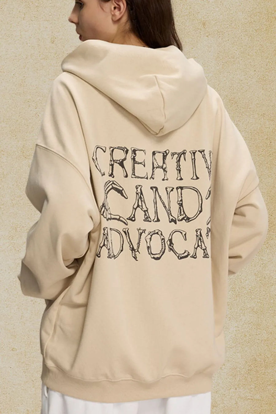 Beige oversized hoodie with black skeleton text graphic on back.