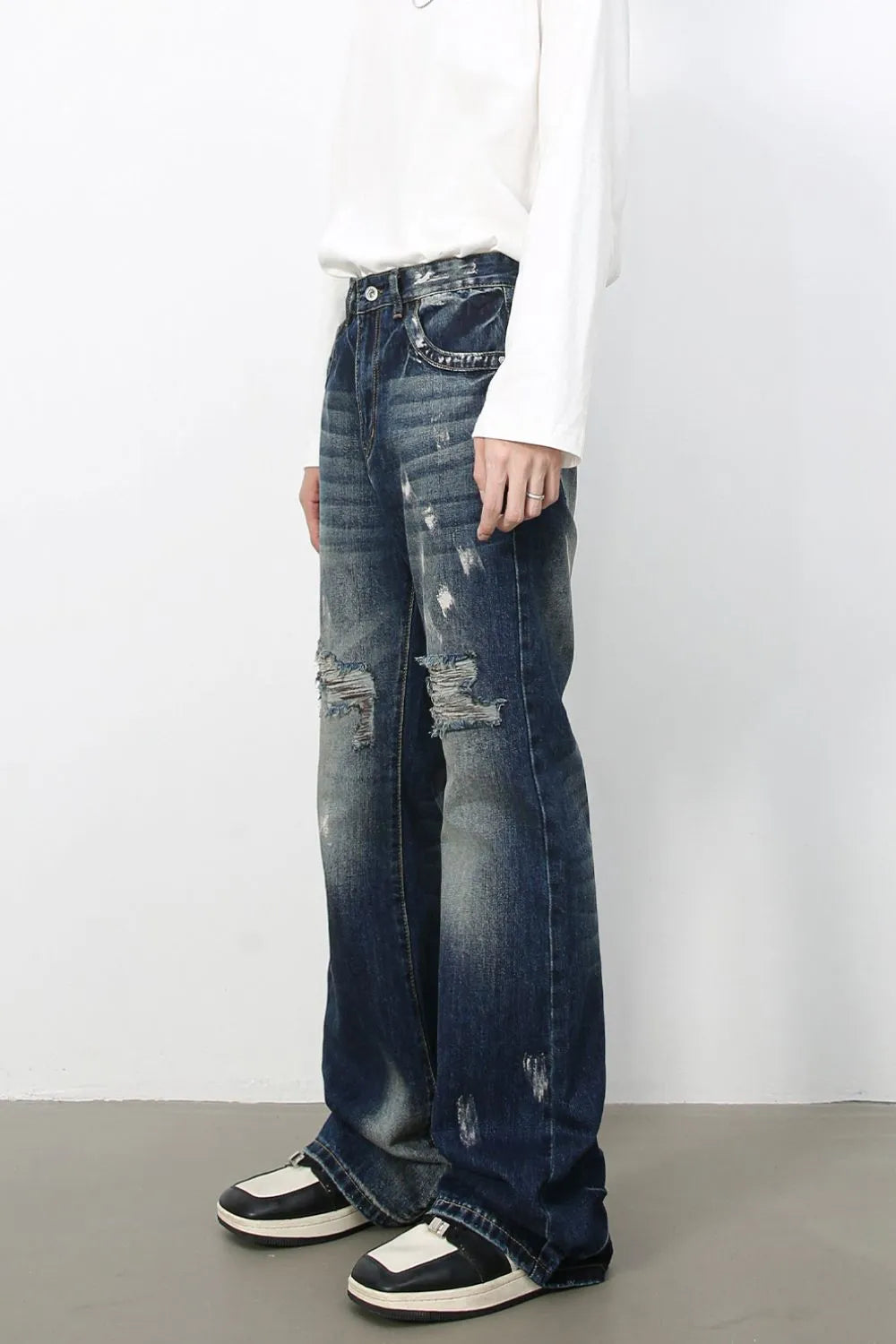 Distressed flare jeans in medium wash denim with raw edge finish and ripped details.