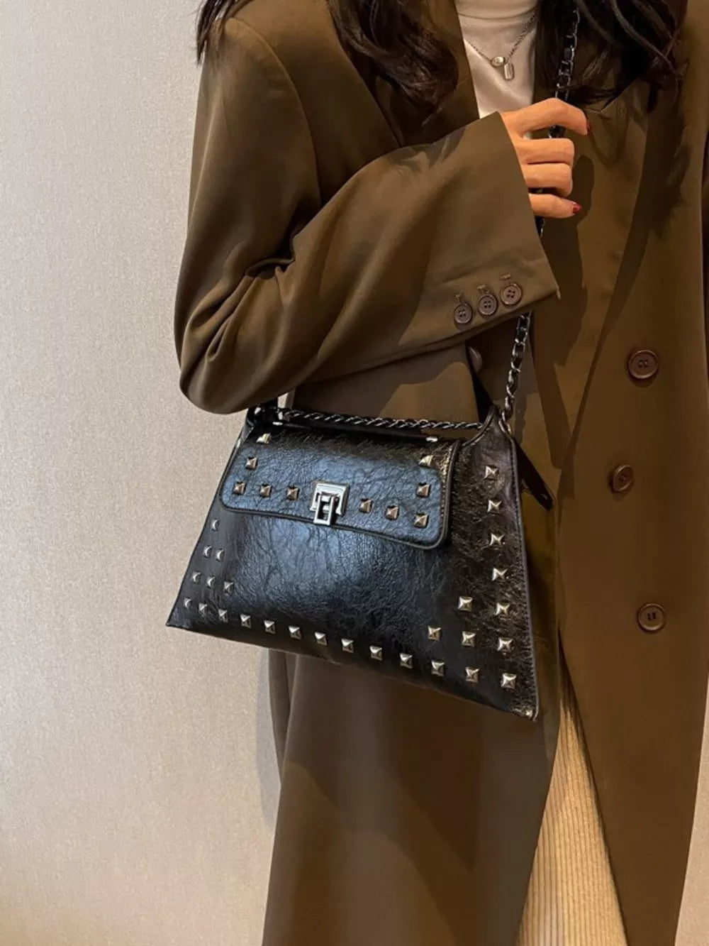 Black embellished chain flap shoulder bag with silver studs and turn-lock closure.