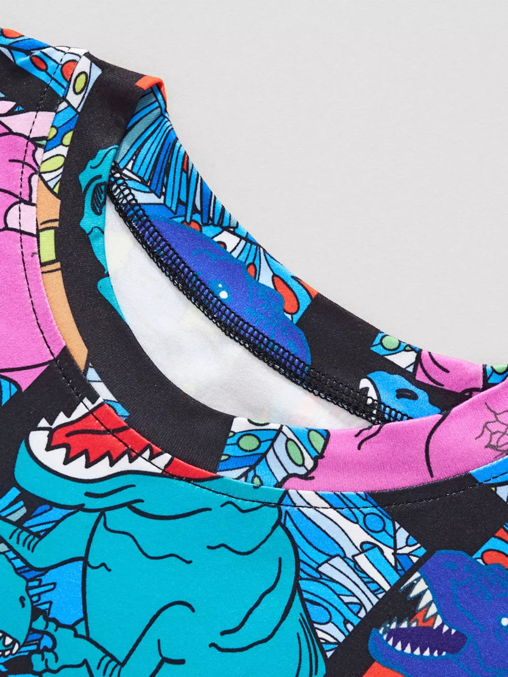 Crew neck t-shirt with a colorful cartoon dinosaur print and black trim.