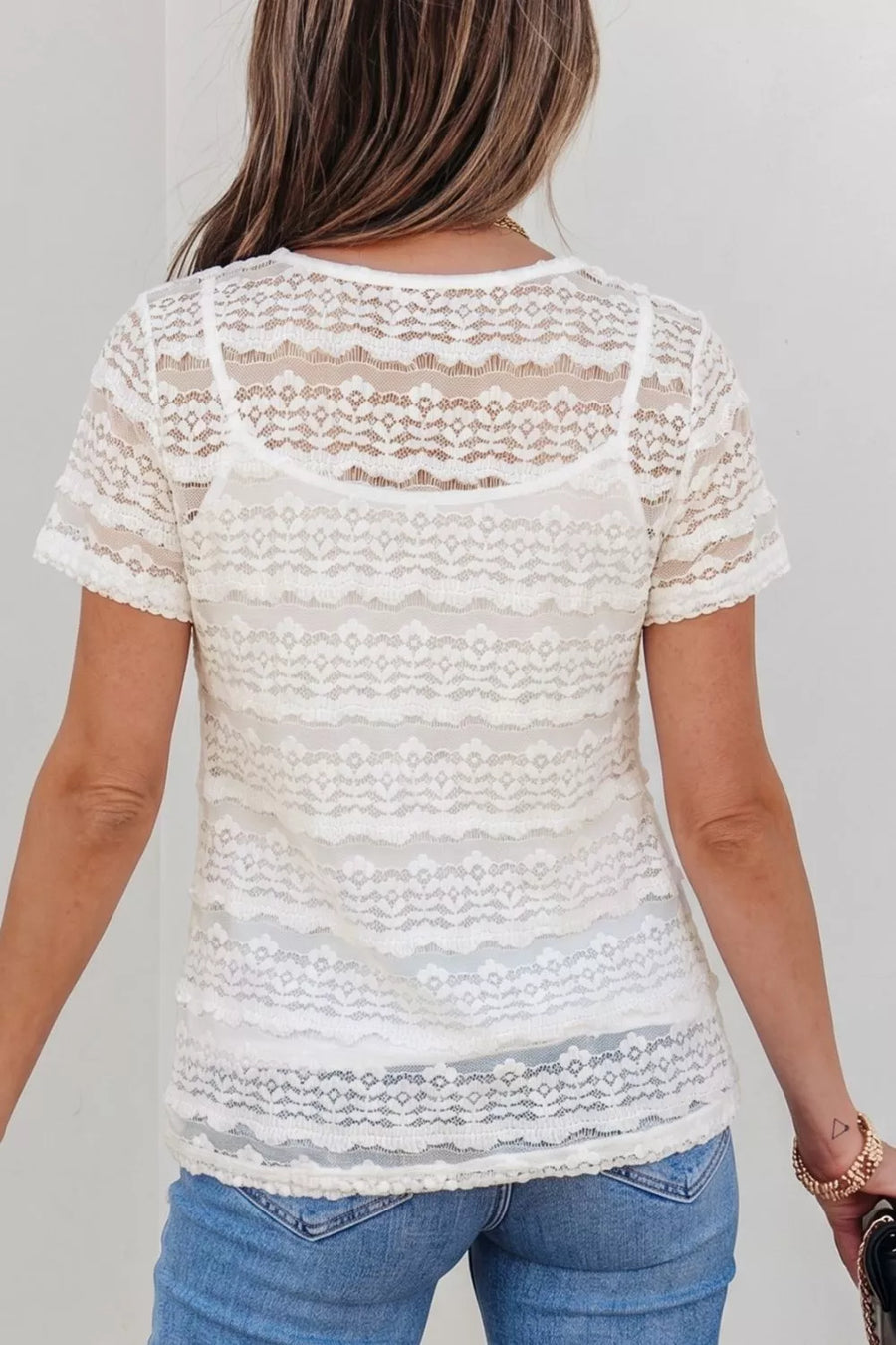 White sheer lace t-shirt with short sleeves and intricate patterned details, worn over a camisole.