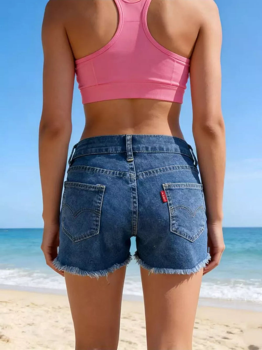Classic blue denim shorts with frayed hem and button fly, shown from the back.