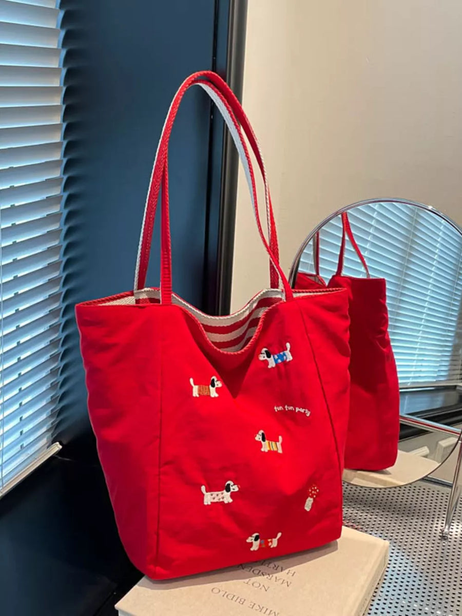 Red shoulder bag with embroidered dachshunds and striped handles.