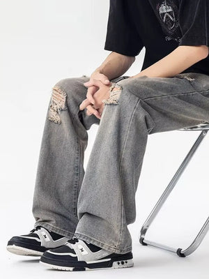 Men's grey loose fit jeans with distressed knee details and a relaxed cut.