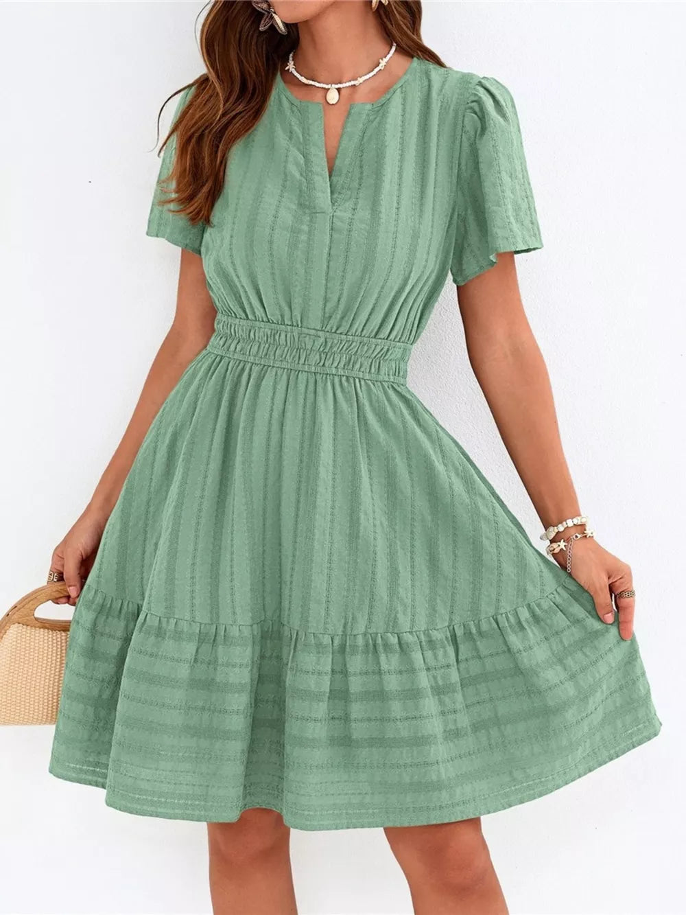 Light green textured V-neck tiered dress with smocked waist and short sleeves.