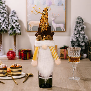 Festive gnome bottle topper with gold sequin hat and reindeer antlers, white beard, and yellow striped sleeves.