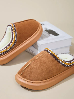 Caramel shearling house slippers with embroidered trim and cozy lining.